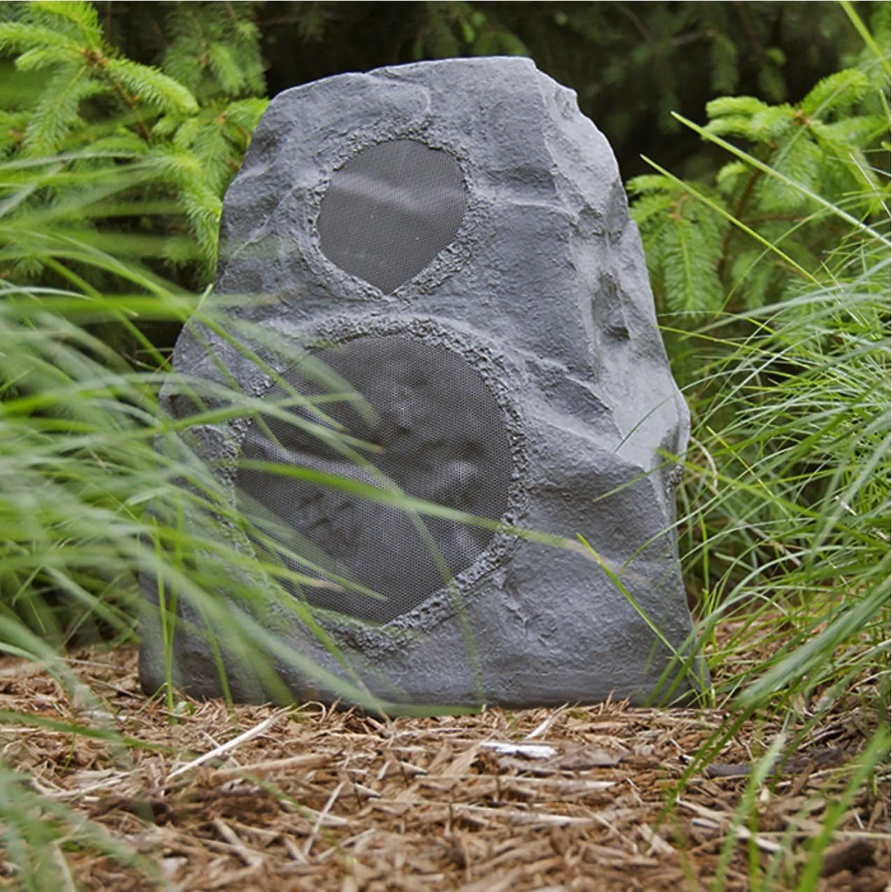 A person sitting across a patio listening while the AWR-650-SM plays in the distance