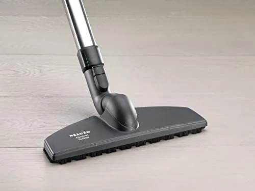 The brush gliding under a low cabinet toe kick during a clean