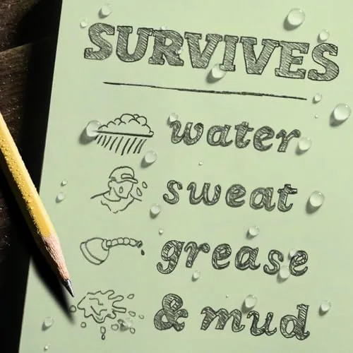 A hand holding the pocket notebook open while writing outdoors