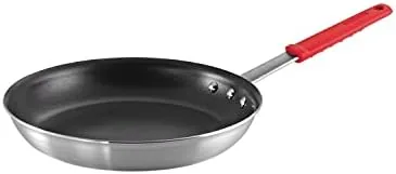 The Tramontina Professional 12 inch frying pan with its red handle on a stove top