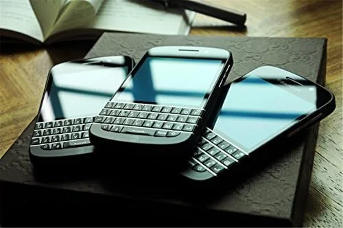 The BlackBerry Q10 charging on a desk beside a laptop