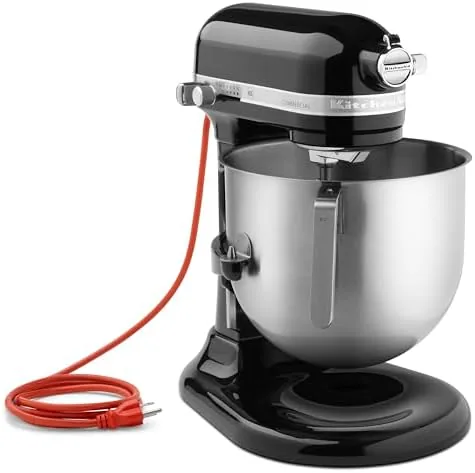 The mixer whipping cream in the large bowl on a busy counter