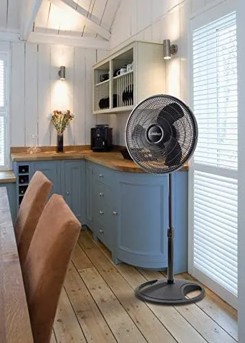 The fan running beside a bed at night with the head tilted toward the mattress