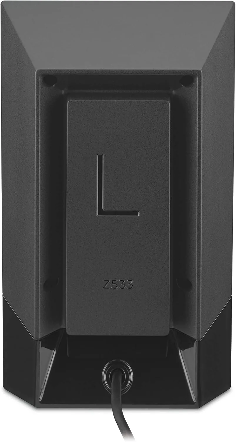 The Logitech Z533 subwoofer on the floor beside a desk with the satellites above