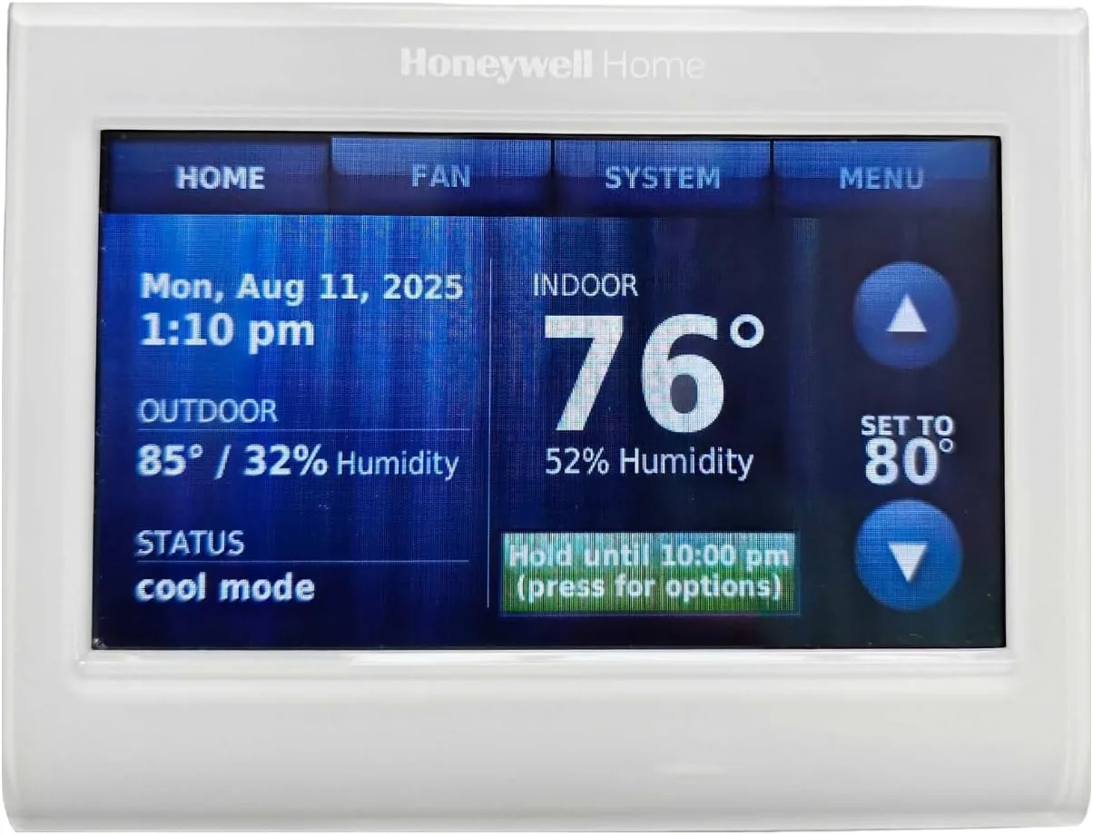 The white Honeywell WiFi thermostat mounted on a living room wall