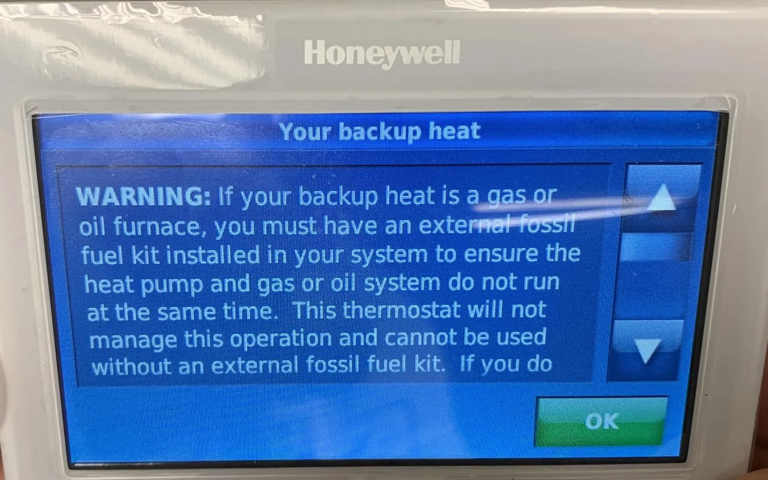 A utility bill on a table next to the thermostat showing a lower heating charge