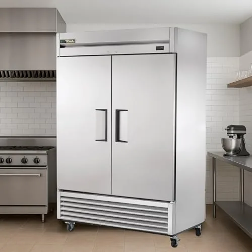 A chef working in front of the True T-49-HC refrigerator in a commercial kitchen