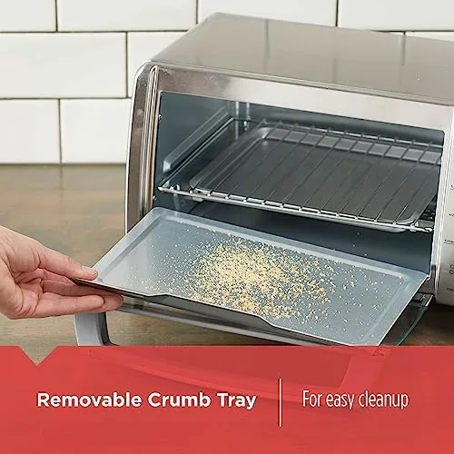 The removable crumb tray of the toaster oven being removed for cleaning