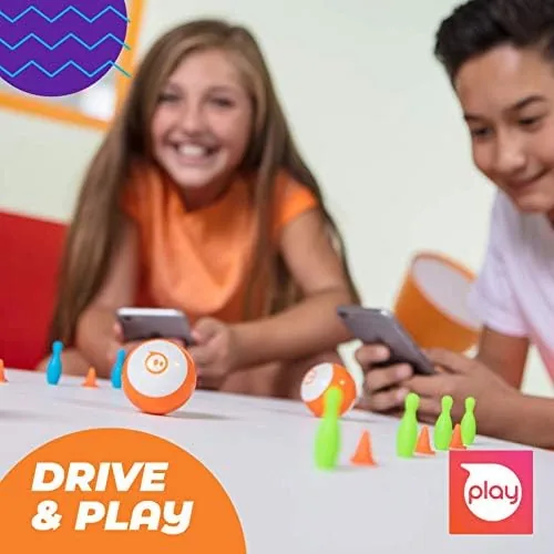 The Sphero Mini charging at its micro USB port beside a tablet