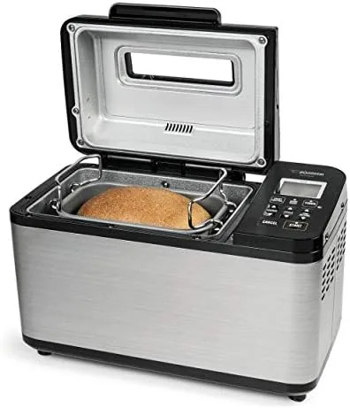 A fresh loaf cooling on a wire rack next to the bread maker
