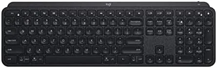 A writer typing on the MX Keys at a home desk with a laptop and monitor