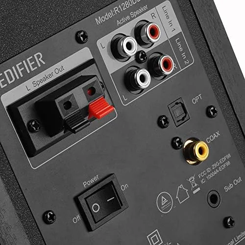 Edifier R1280DBs speakers beside a desktop monitor with the remote