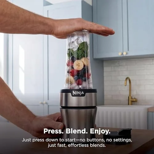 The blender cup filled with a smoothie of berries, banana, and ice