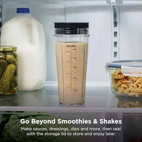 A person carrying the blender cup with a spout lid out the door