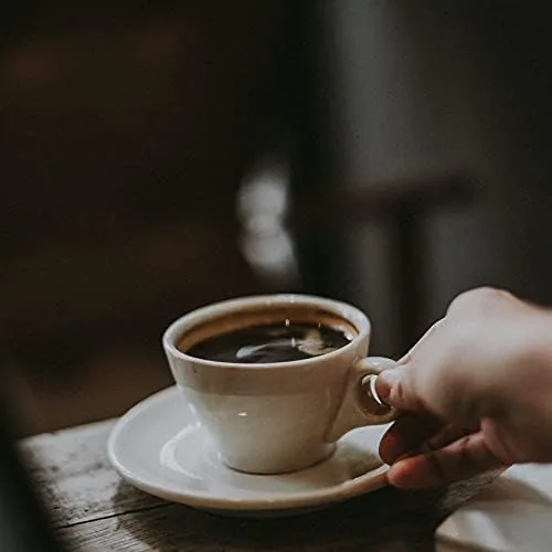 Turkish coffee with crema served in a demitasse beside the smaller pot