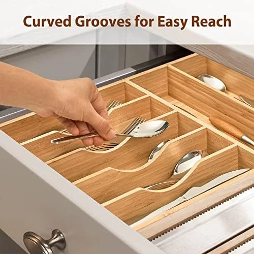 Kitchen drawer fully organized with bamboo tray and folded towels beside it