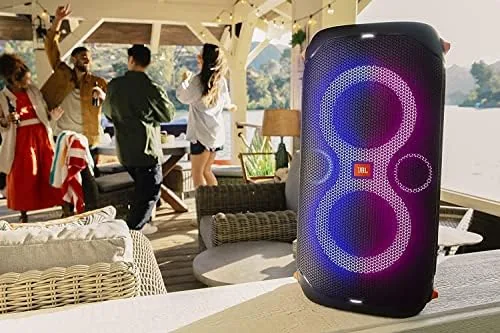 Someone singing into a microphone connected to the PartyBox 110 at a backyard gathering