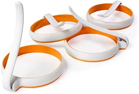 Four silicone fried egg rings resting on a skillet