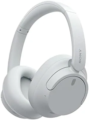 White Sony WH-CH720N headphones resting on a desk next to a laptop in a home office