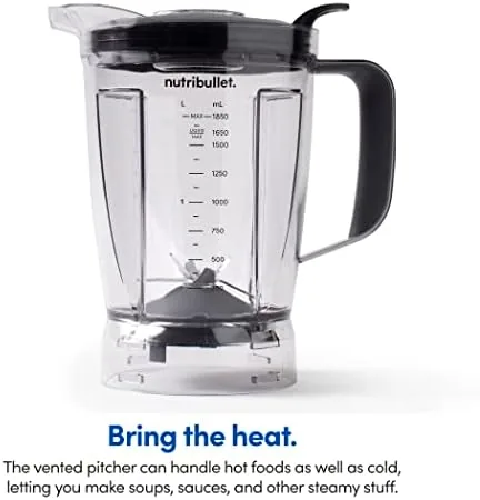 A pitcher of blended soup being poured with steam rising from the blend