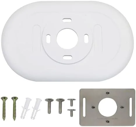 White Nest thermostat wall plate mounted on a wall next to a Nest thermostat