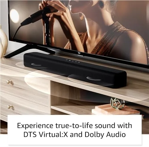 Amazon Fire TV Soundbar under a TV with a Fire TV remote on the sofa