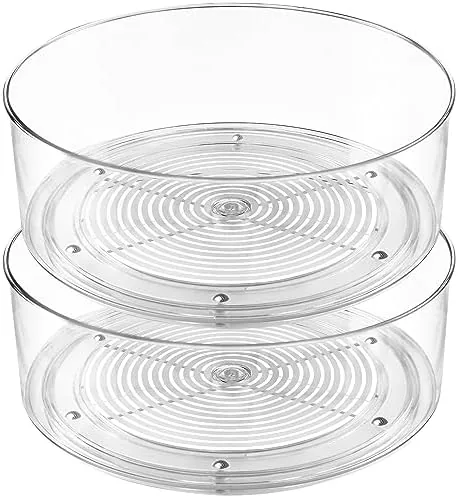 Two clear lazy susan turntables sitting side by side on a counter