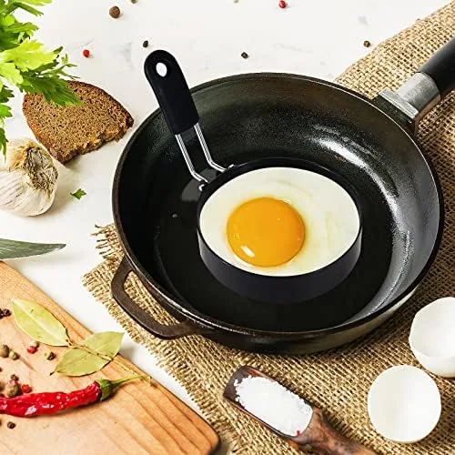An egg being cracked into the center of an egg ring on a frying pan