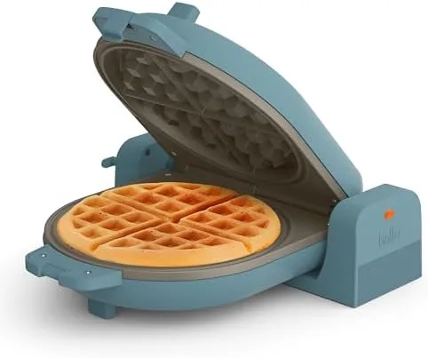 The Surf green bella Fits-Anywhere waffle maker on a kitchen counter with a plate of waffles