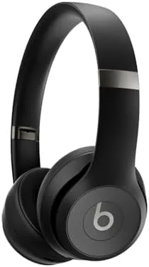 Beats Solo 4 headphones in Matte Black on a hotel bed