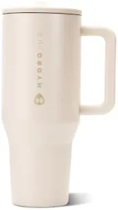 The cream HydroJug Traveler tumbler with its lid and straw on a kitchen counter