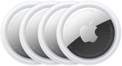 Four Apple AirTags laid out on a table with a keyring and a wallet