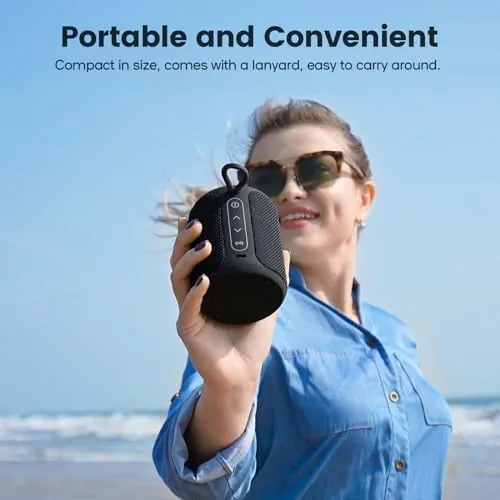 The speaker sitting on a beach towel in the sand with water in the background