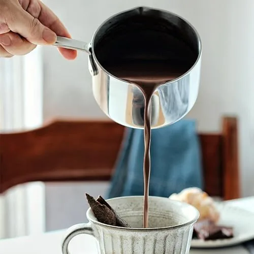 Steaming cup of coffee beside the milk pot after heating