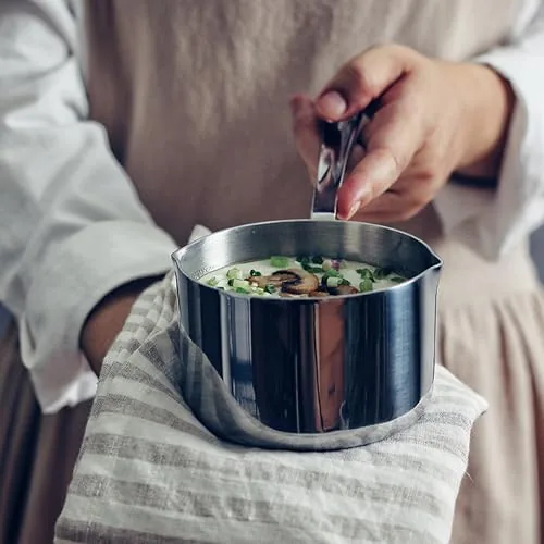 The stainless milk pot next to a nonstick pan and an enameled pot for comparison