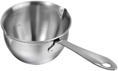 The milk pot being rinsed in a kitchen sink after heating milk