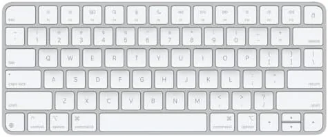 Apple Magic Keyboard on a desk beside a MacBook