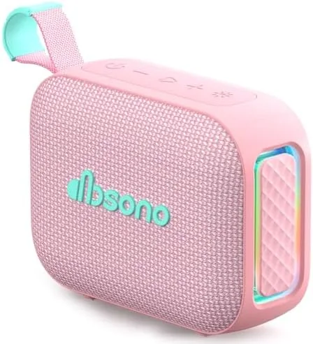 The pink dbsono portable Bluetooth speaker on a beach towel beside a bag