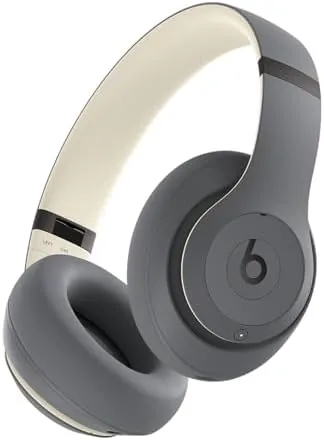 Beats Studio Pro Sand Gray over-ear headphones on a table with a passport