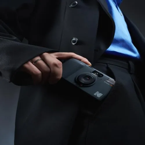 The camera being carried outdoors in a hand along with a small film roll