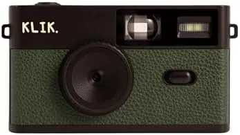 The green Klik screen-free camera sitting on a table beside a stack of printed photos