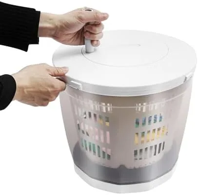 The 2 in 1 manual clothes washer set up at a campsite with a bucket of water nearby